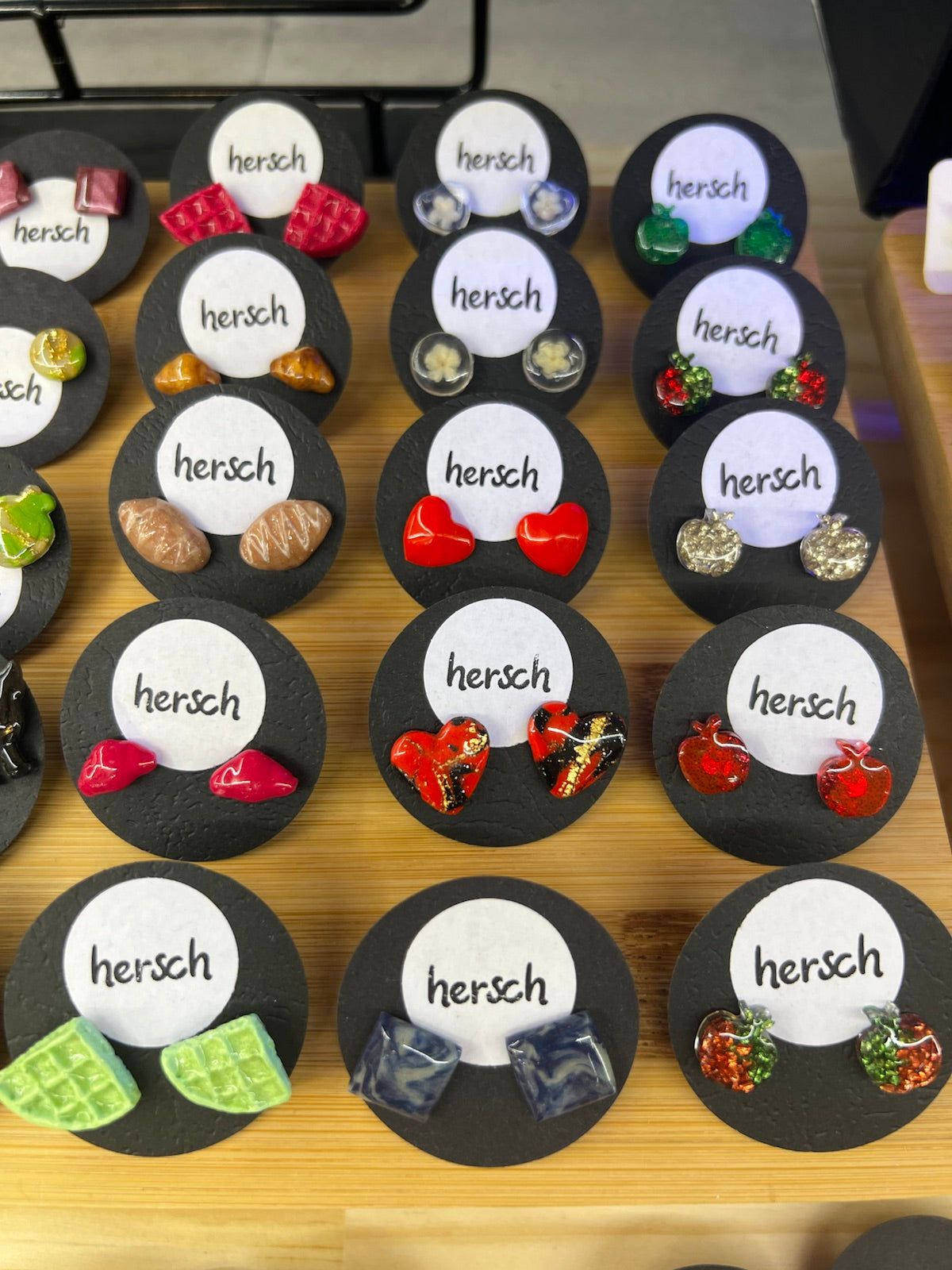 Colourful handmade Hersch earrings arranged on a market table
